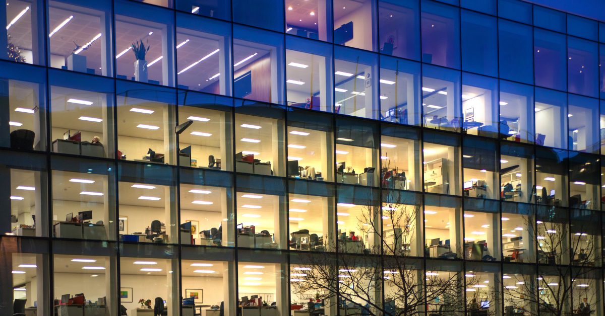Photograph of an office with its lights on from outside at night